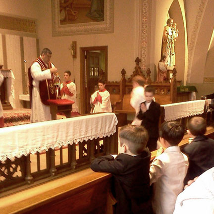 Father Zepeda Administers First Holy Communion as Each Child Approaches in Turn