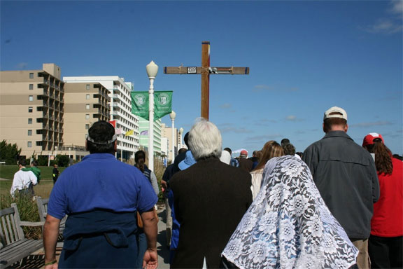 The large crowd carries a homemade processional cross.